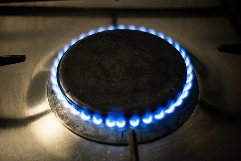 Close-up of a gas hob burner with an even blue flame