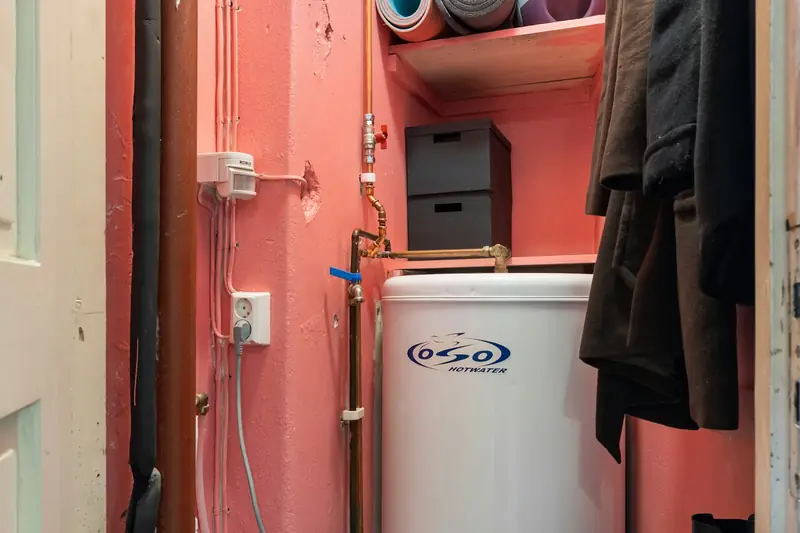 Hot water cylinder and pipework inside an airing cupboard