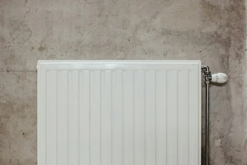 White single panel radiator with a thermostatic valve on a grey wall