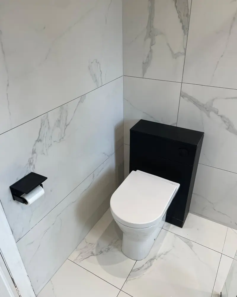Back-to-wall toilet on a black concealed cistern unit with marble-effect wall and floor tiles