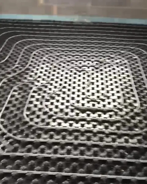 Underfloor heating pipe pressed into a studded overlay panel in a spiral pattern