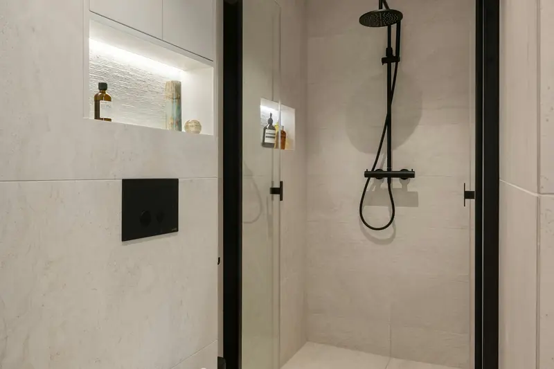 Level-access wet room with a black shower mixer, wall-hung toilet and large-format tiles